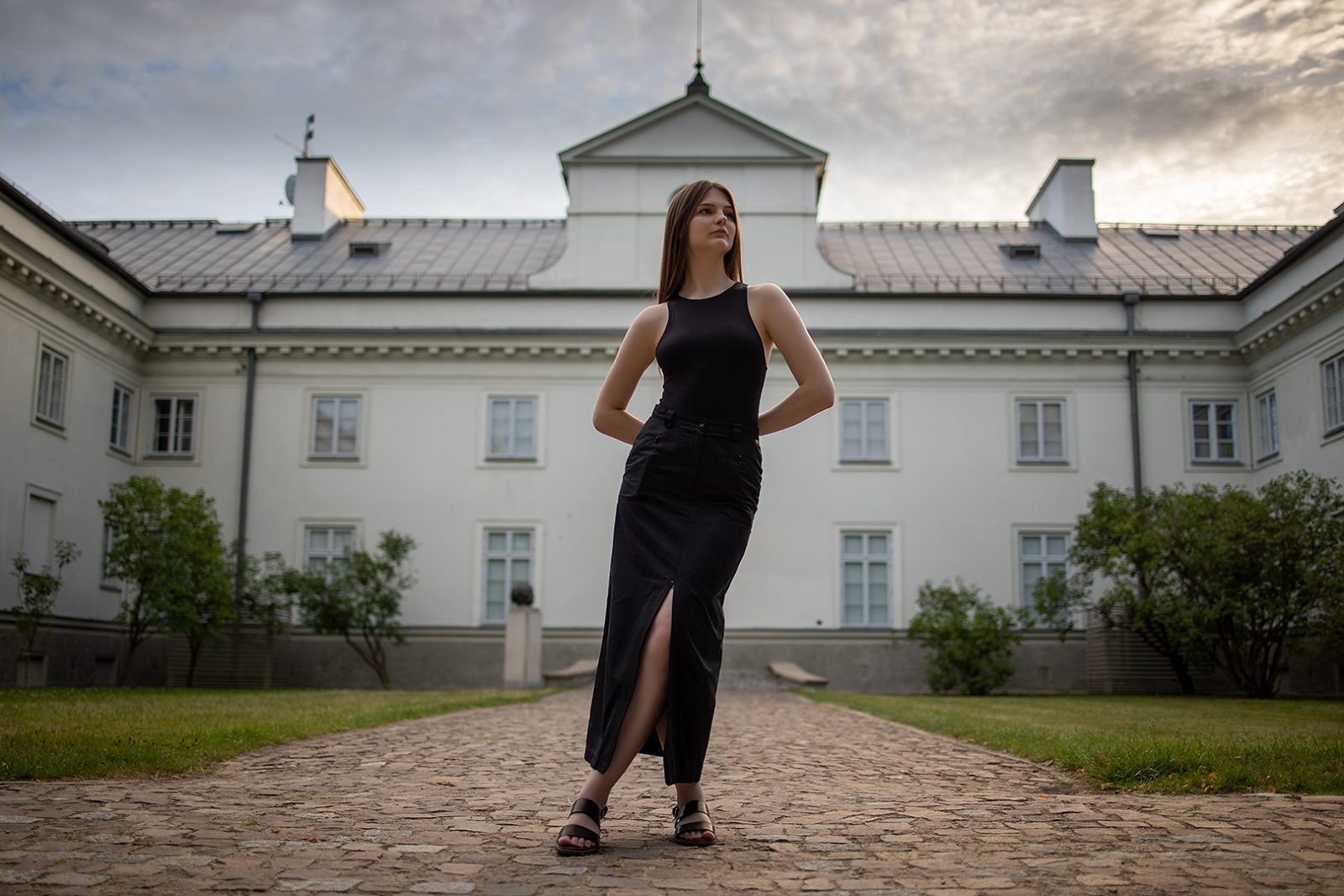Woman in a black dress before a manor facade