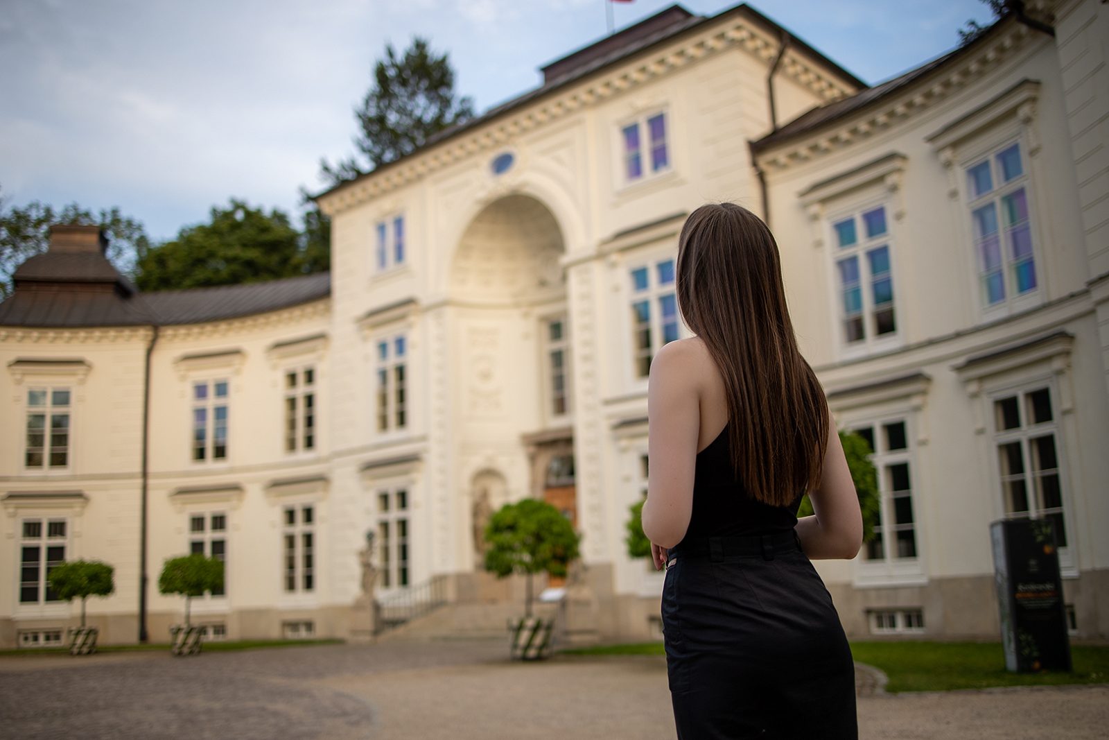 Woman in a black dress looking at a manor building