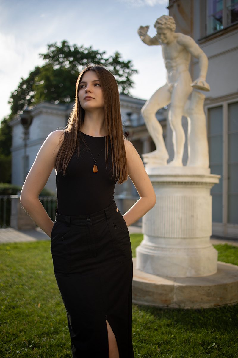 Portrait of a woman in a black dress beside a garden statue