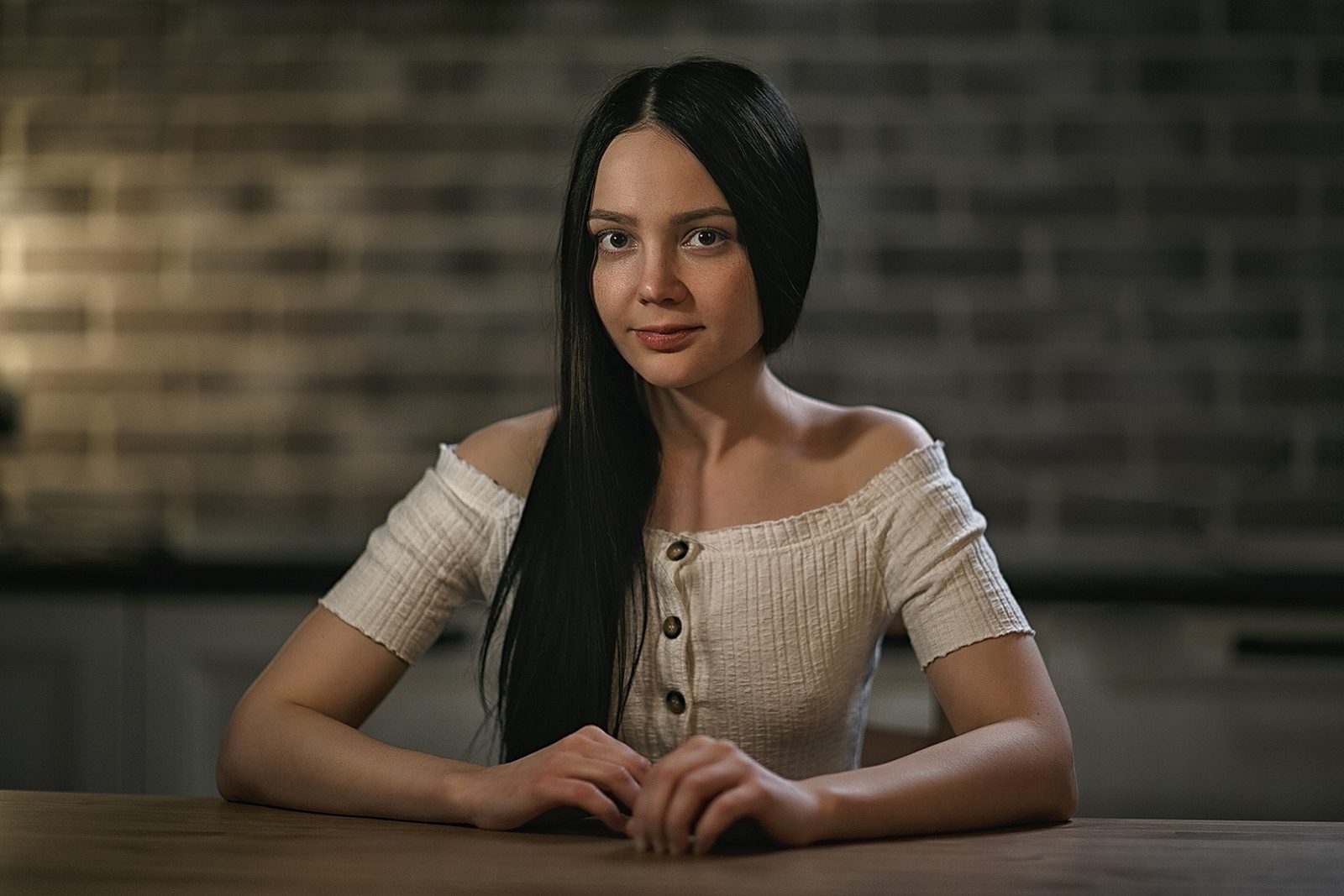 Studio portrait of a woman in a light blouse at a table