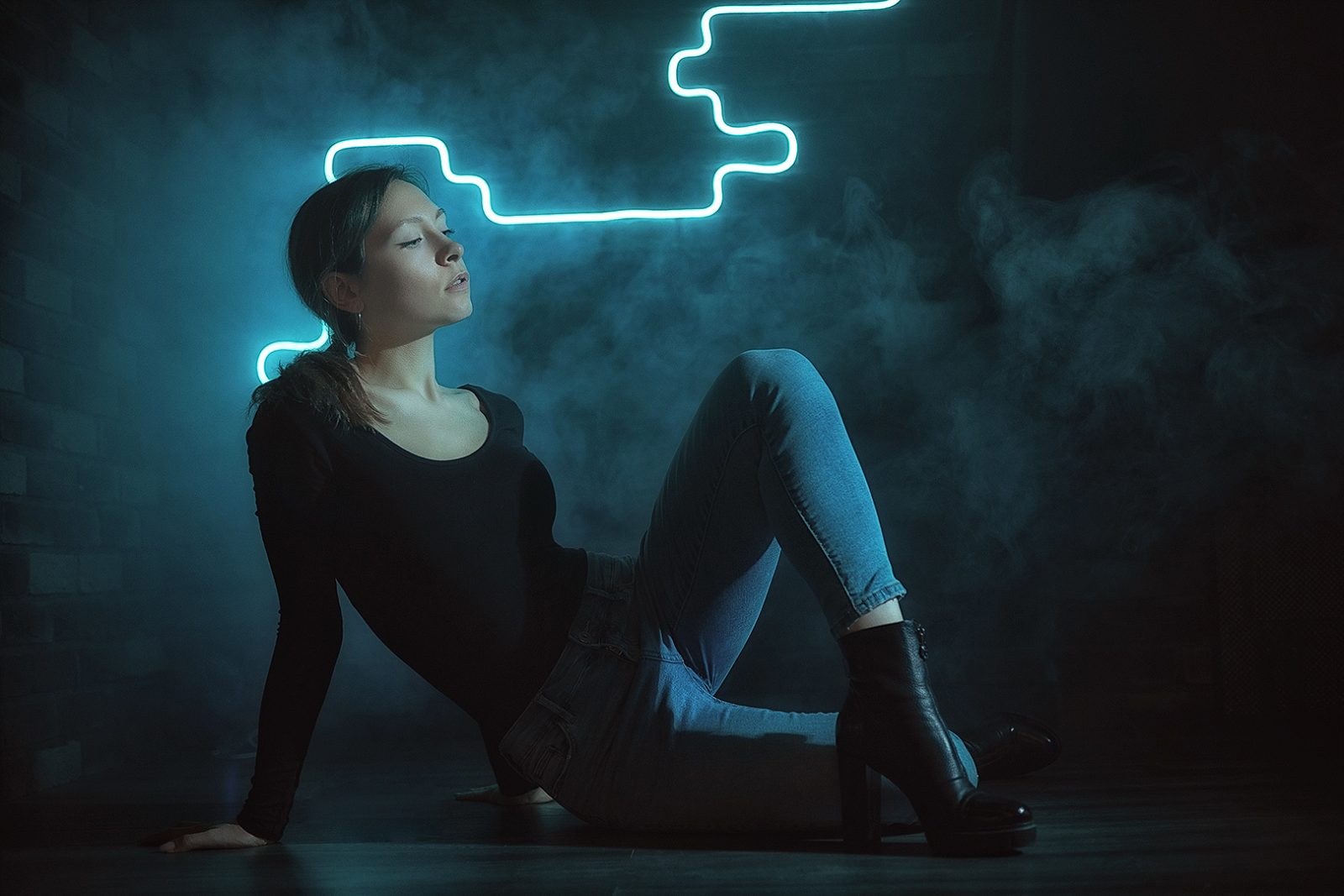 Woman sitting by a wall in blue neon light