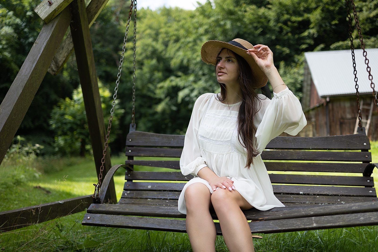 Woman in a white dress sitting on a garden swing
