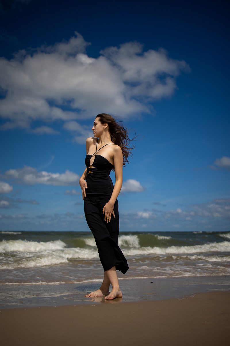 Woman in a black dress standing by the sea